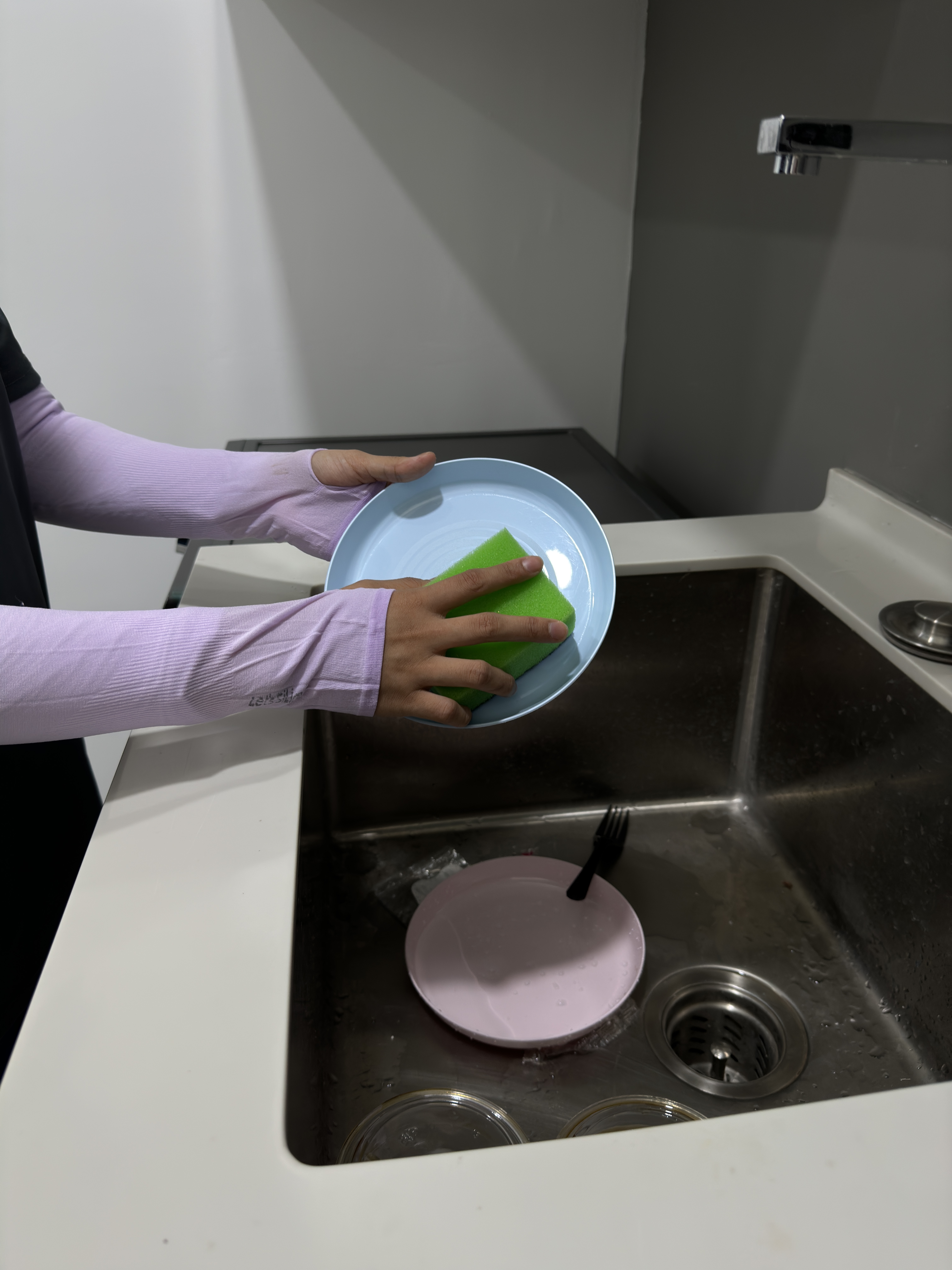 Hands washing a plate at a sink